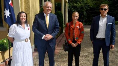 Outgoing Australian of the Year Grace Tame stands stony faced next to the prime minister.